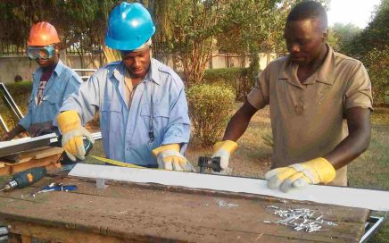 3 men wearing TAG Fabrications overalls, scaling steel and aluminium materials in Uganda